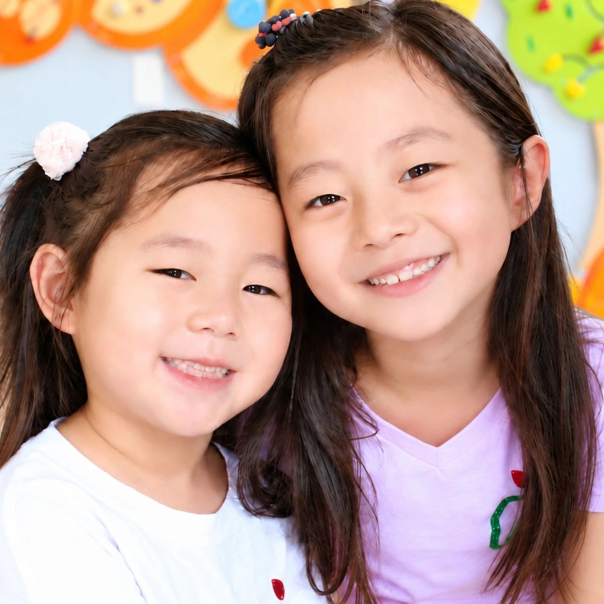 Two smiling girls cheek to cheek in the La Petite Dent waiting area