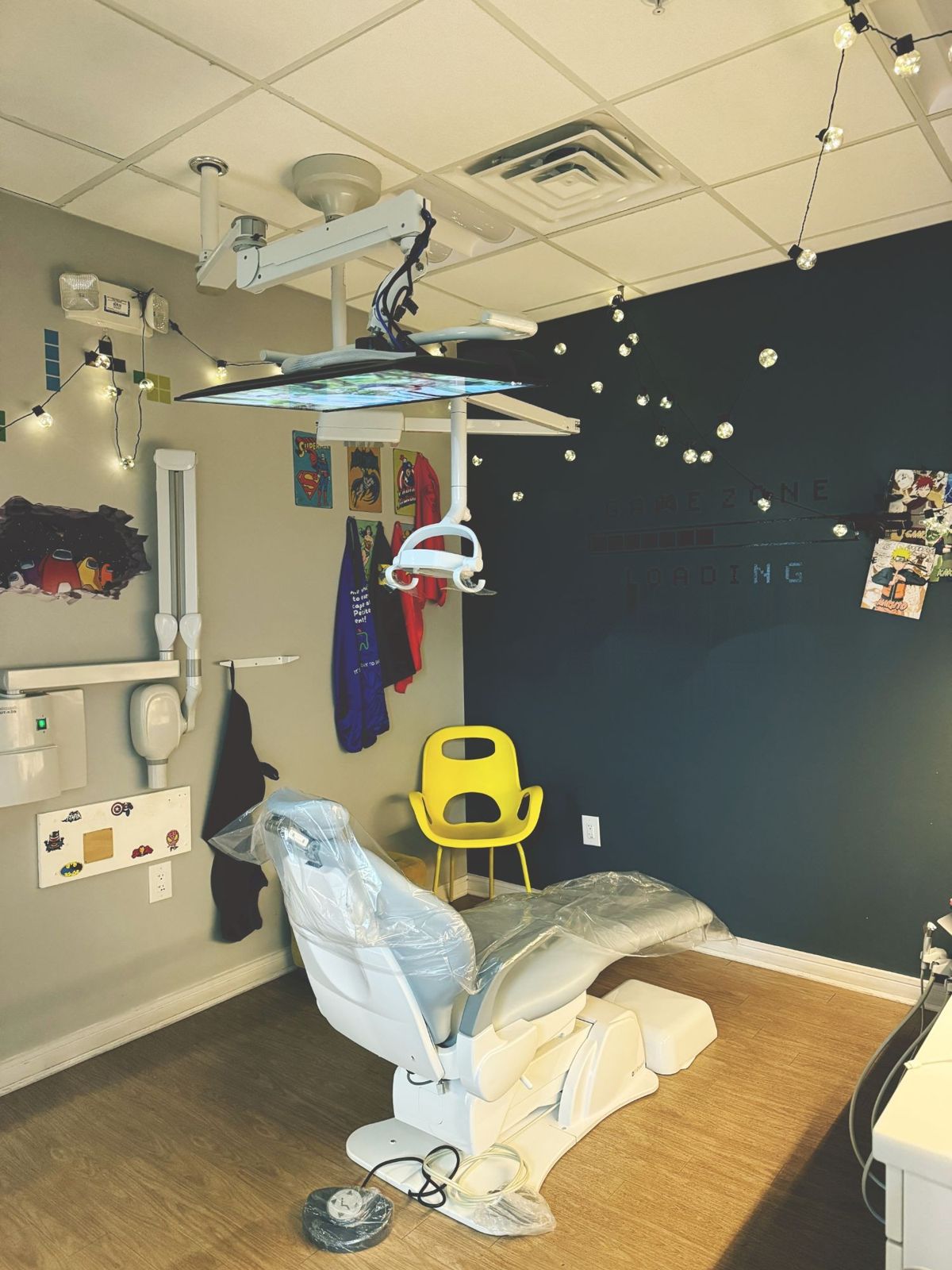 The Game Room: a treatment room with string lights, superhero posters, and a video-game themed wall