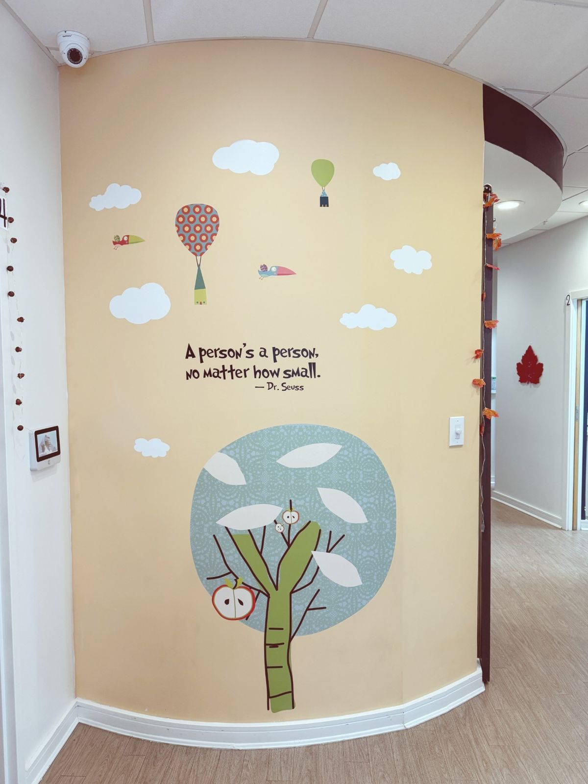 A painted wall with a tree, hot-air balloons, and the quote: A person's a person, no matter how small